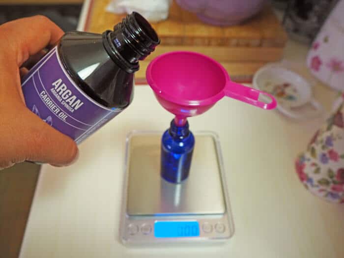 Pouring argan oil on bottle to make hair serum