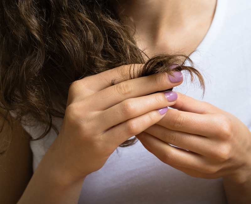 Female looking holding hair split ends.